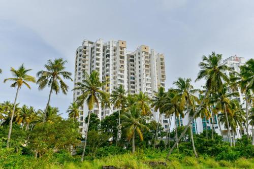 a tall building with palm trees in front of it at Super Hotel O Tyche Stays in Trivandrum