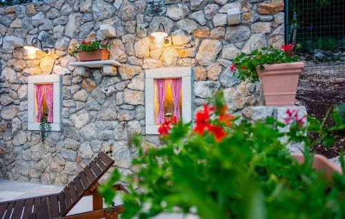 a stone wall with three windows with flowers and plants at Villa Imortele aria with pool by Villas Guide in Cres