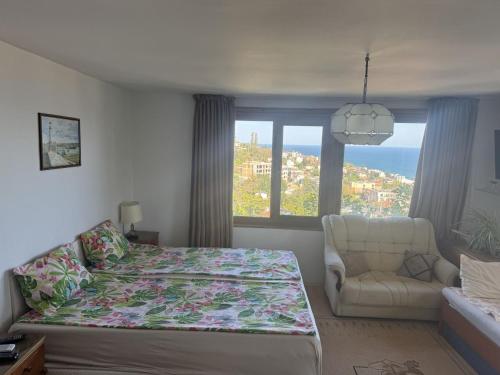 a bedroom with a bed and a chair and a window at Етаж от къща - Желкови in Varna City