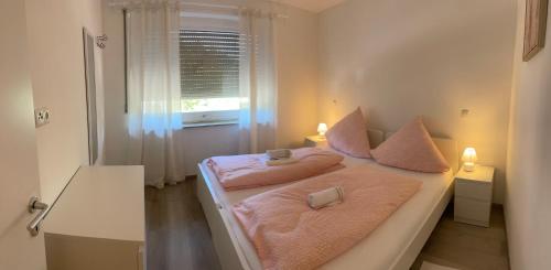 a bedroom with a bed with pink sheets and a window at Holunder nah am Waldsee 2 in Rieden