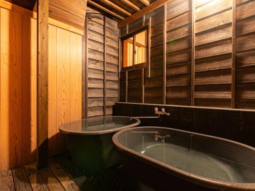 a wooden bathroom with a tub and a window at NIPPONIA Sado 佐渡相川 金山町 in Sado