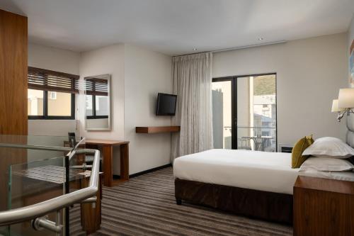a hotel room with a bed and a balcony at Premier Hotel Cape Town in Cape Town