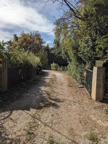 a dirt road with a fence and trees at Gite Au Moulin in Orbessan