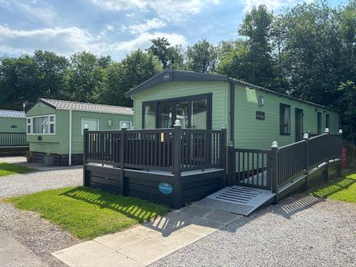 a green tiny house with a black fence at 10 Borwick Lakes, Carnforth - En suite - King size bed in Carnforth