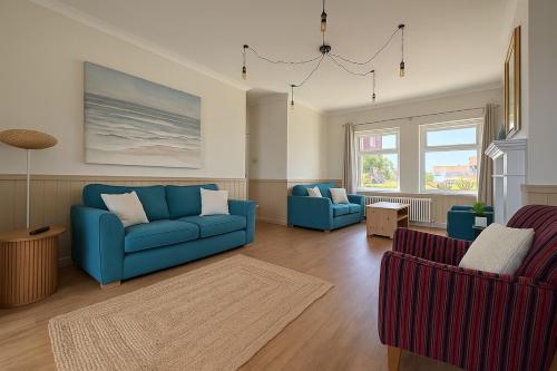 a living room with two blue couches and two chairs at 4 Seaview Sheringham in Sheringham