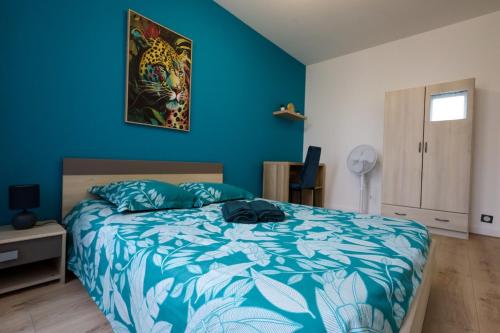 a bedroom with a bed and a blue wall at Chez Viticka in Saint-Vulbas