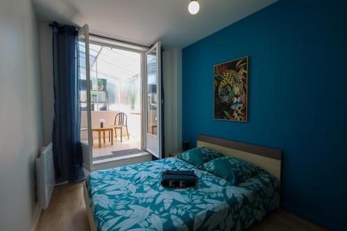 a blue bedroom with a bed with a bag on it at Chez Viticka in Saint-Vulbas