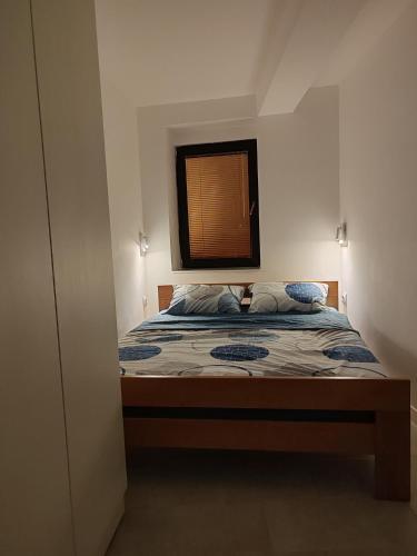 Un dormitorio pequeño con una cama con ventana. en Maksimilijan, en Ohrid