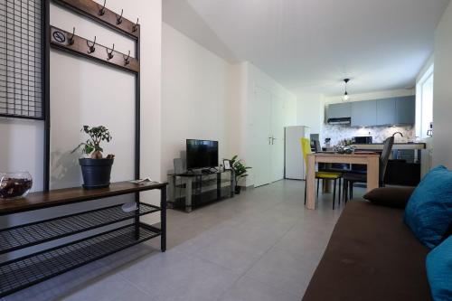 a living room with a couch and a table and a kitchen at Chez Viticka in Saint-Vulbas