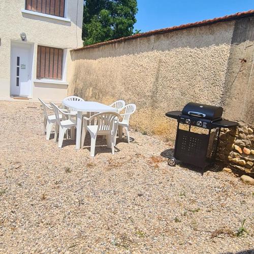 a table and chairs with a grill and a table and chairs at Chez Viticka in Saint-Vulbas