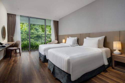 a hotel room with two beds and a window at Flamingo Resort Cat Ba in Cat Ba