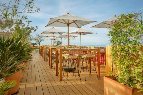 a row of tables and chairs with umbrellas on a deck at AC Hotel by Marriott Nice in Nice
