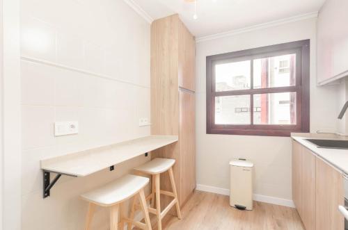 a kitchen with white walls and a counter and stools at Apartamento Bilua in Luanco
