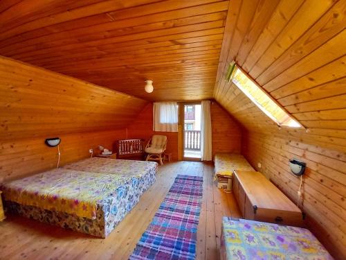 une chambre mansardée avec deux lits et un banc dans une pièce dans l'établissement Drevenica pod Kráľovou hoľou, à Šumiac