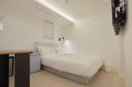 a white bedroom with a bed and a desk at Aank Hotel Seoul Sinchon in Seoul