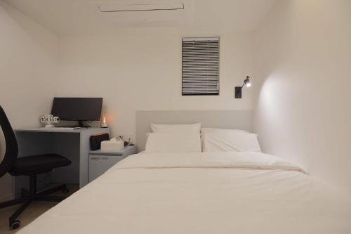 a bedroom with a bed and a desk with a computer at Aank Hotel Seoul Sinchon in Seoul