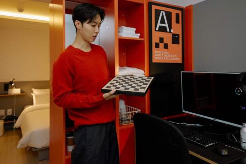a young man holding a chessboard in a room at Aank Hotel Seoul Sinchon in Seoul