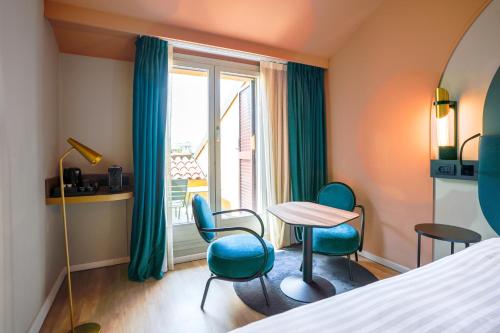 a room with a bed and chairs and a table and a window at Mercure Bologna Centro in Bologna
