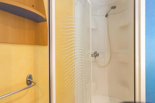 une douche avec une porte en verre dans une salle de bain dans l'établissement Mobilhome La Clairière, à Saint-Pompont