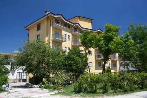 a large yellow building with trees in front of it at Hotel Aquila in Scoppito