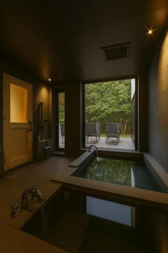a bathroom with a tub with a view of a patio at Villa Moriyoshi in Tomakomai