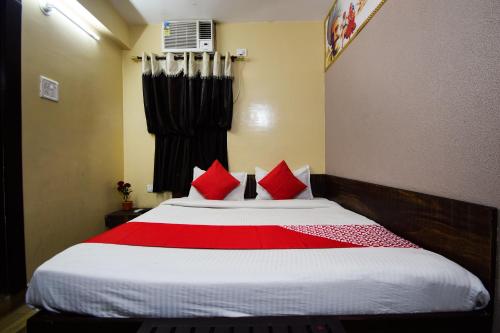 a bedroom with a large bed with red pillows at Hotel O Kota Airport Formerly Vaishnavi in Kota