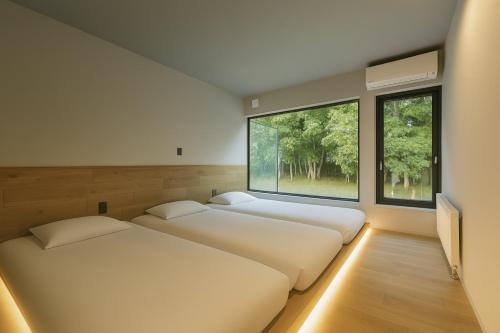 two beds in a room with two windows at Villa Moriyoshi in Tomakomai