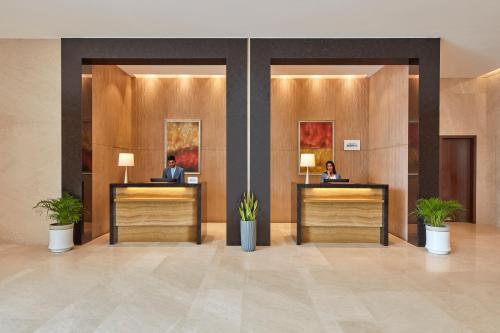 a lobby with two people sitting at reception desks at Courtyard by Marriott Kochi Airport in Nedumbassery