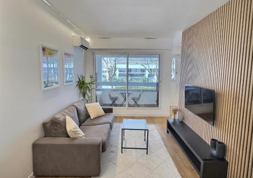 ein Wohnzimmer mit Couch und Flachbildfernseher in der Unterkunft Centre-Ville, 5 min de la Plage, parking, piscine in La Grande-Motte