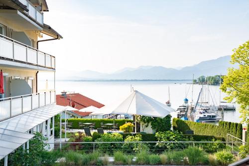 a patio with a white umbrella and a marina at ChiemseeStern Vacation & Recreation "Adults Only" in Gstadt am Chiemsee