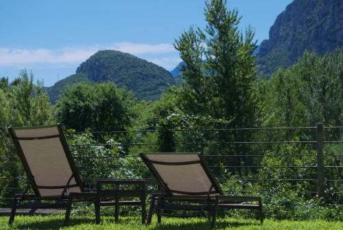 two chairs sitting in the grass with mountains in the background at APPARTAMENTO I SENTIERI 29D in Dro