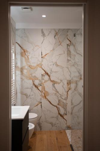 a bathroom with a white toilet and a marble wall at G&G Luxury Rooms in Bari