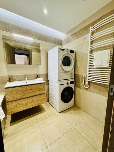 a bathroom with a washing machine and a sink at Evoli Apartman in Debrecen