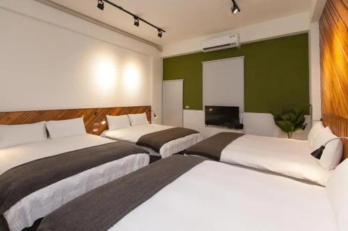 a hotel room with two beds and a flat screen tv at 廷海特潮流民宿 漢中館 民宿編號1746 寵物友善陽台房 近微光集與鐵道藝術村 in Taitung City