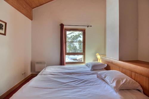 a bedroom with a white bed with a window at ARC 1950 - Appartement 10 personnes Duplex Cheminée - ski aux pieds - Sauna, Hammam, Jacuzzi, Piscine in Arc 1950