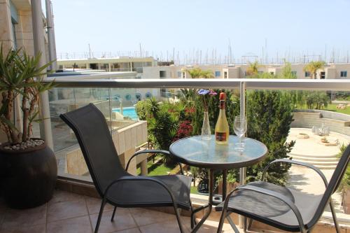 a balcony with a table and two chairs and a bottle of wine at Nomi Suites Marina Herzelia in Herzelia 