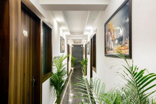 a hallway with plants and paintings on the walls at Hotel Mehak Palace By Aura in Noida