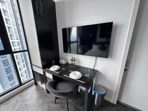 a black desk with a chair and a television in a room at Scartlez suites KLCC by Dream in Gua Sai