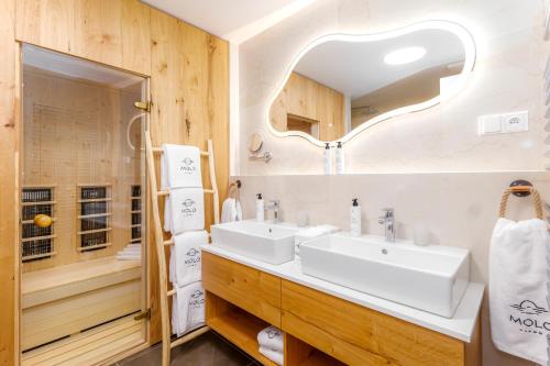 a bathroom with two sinks and a mirror at MOLO LIPNO RESIDENCE in Lipno nad Vltavou