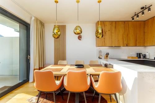a kitchen with a wooden table and orange chairs at MOLO LIPNO RESIDENCE in Lipno nad Vltavou