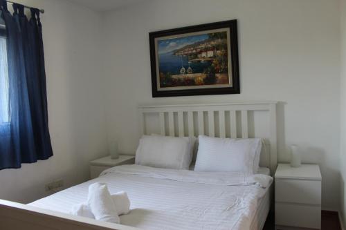 a bedroom with a white bed with a picture on the wall at Nomi Suites Marina Herzelia in Herzelia 