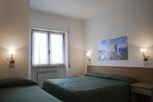 a bedroom with two beds and a window at Hotel Aquila in Scoppito
