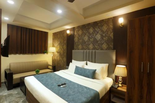 a hotel room with a large bed and a couch at Hotel Mehak Palace By Aura in Noida