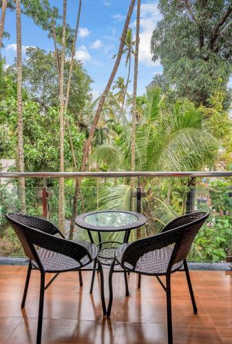 three chairs and a table on a balcony with trees at Hotel Ocean Prosper in Nagaon