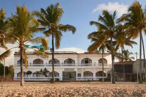 un edificio bianco con palme di fronte di Hotel Albemarle Galapagos Beachfront a Puerto Villamil