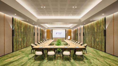 a conference room with tables and chairs and a screen at Holiday Inn Resort Bintan Lagoi Beach by IHG in Lagoi