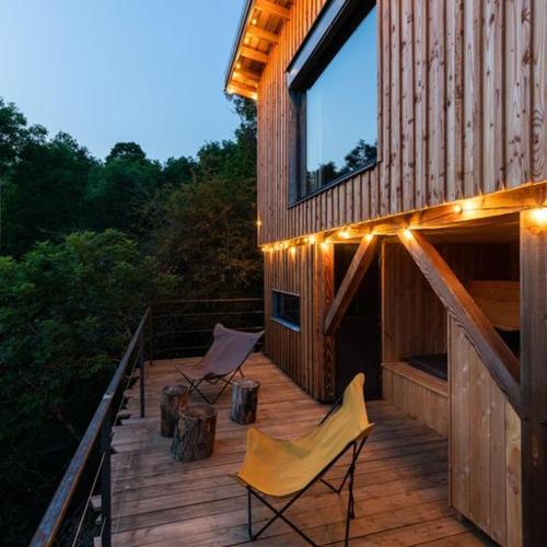a wooden deck with two chairs and lights on it at La Muzetiere Cabane du crêt in Chamelet