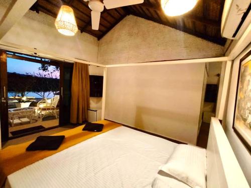 a bedroom with a white bed and a large window at Midsummer Night Dreams in Canacona