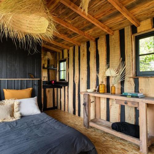 a bedroom with a bed in a wooden room at La Muzetiere Cabane du crêt in Chamelet