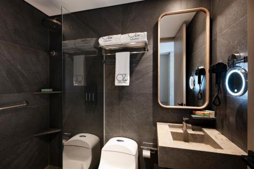 Un baño con dos inodoros, un lavabo y un espejo. en OZ Hotel Collection, en Cartagena de Indias